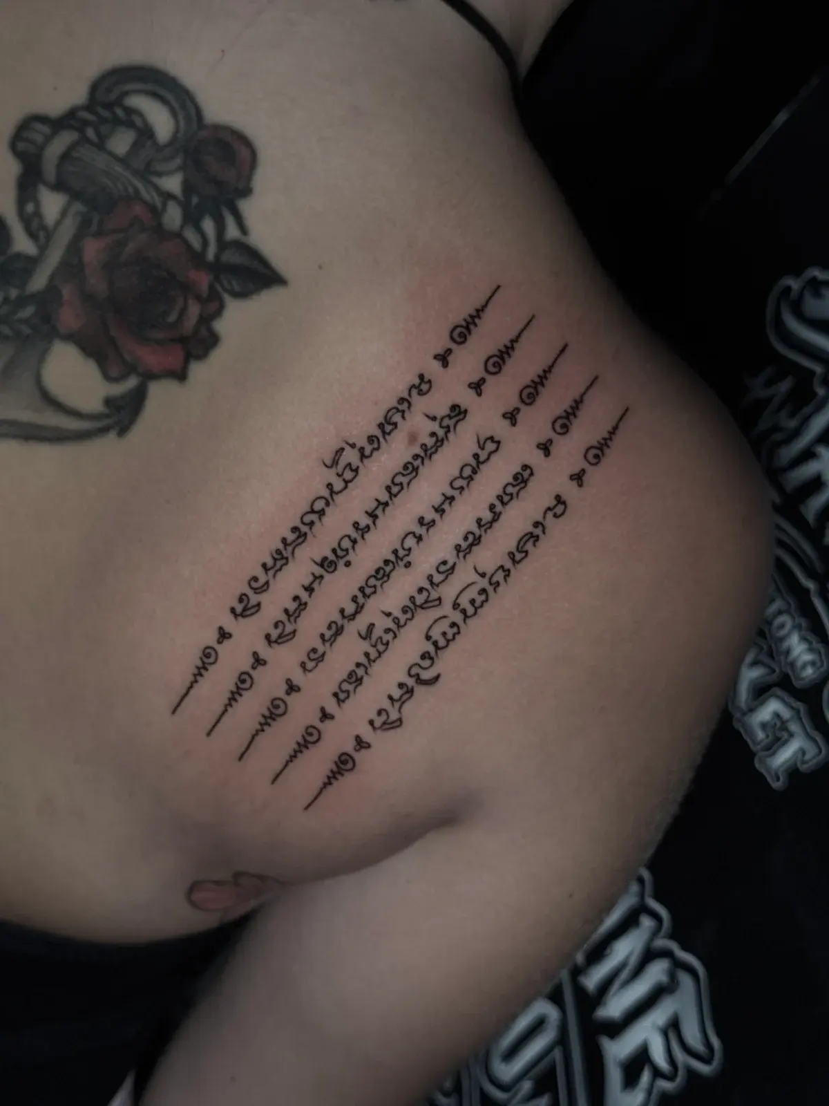 Hah Taew (Five Sacred Lines) Sak Yant with five vertical Khom script rows and unalome symbols on the ribcage at Bloodline Tattoo Phuket.
