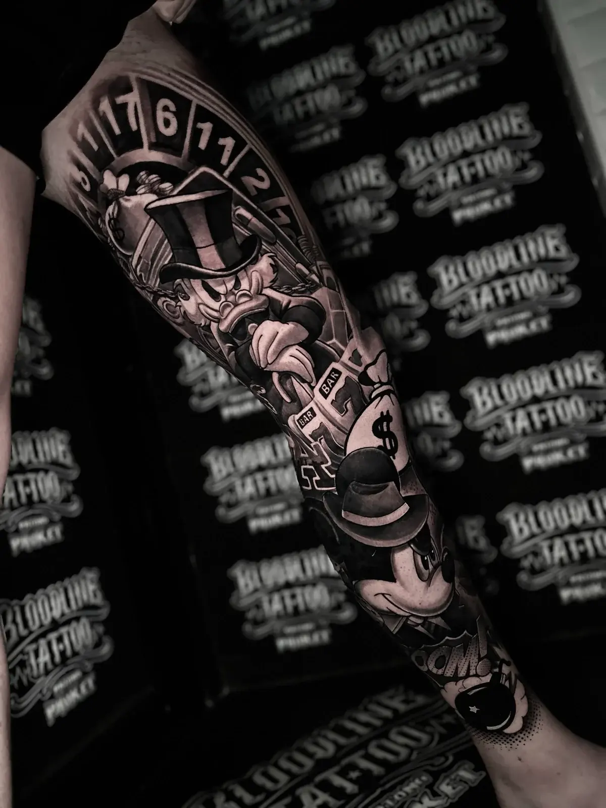 Chicano leg tattoo with Scrooge McDuck, fedora Mickey Mouse, a roulette wheel, slot reels, money bags, and a cartoon bomb at Bloodline Tattoo Phuket.