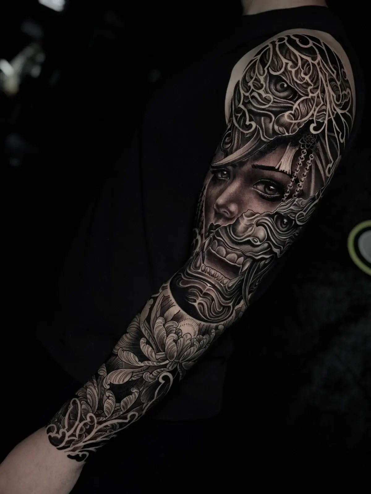 Japanese black and grey full sleeve blending a woman's portrait with Hannya mask, chrysanthemums, and wind-wave mikiri at Bloodline Tattoo Phuket.