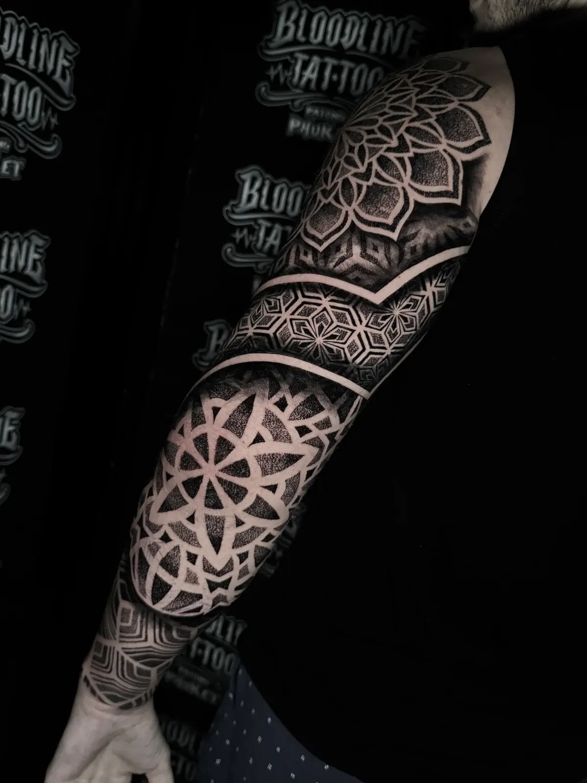 Black and grey mandala sleeve with dotwork shoulder and elbow mandalas separated by a hexagonal star band at Bloodline Tattoo Phuket.